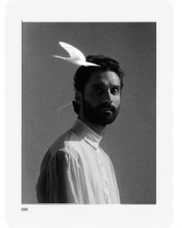 Amos Le Blanc standing outdoors wrapped in an oversized white duvet