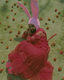 Amos Le Blanc in a red costume and tall pink rabbit ears surrounded by strawberries